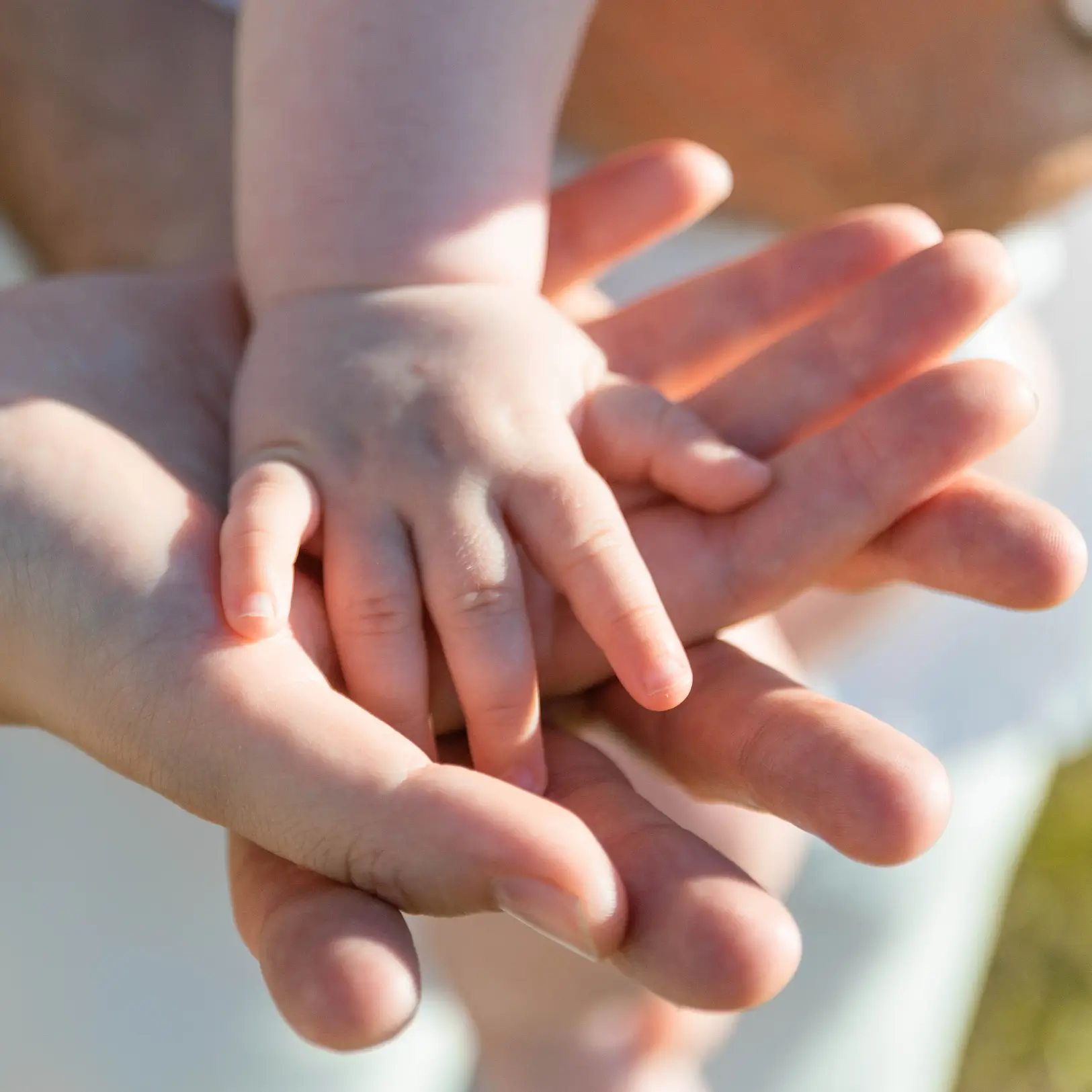 infant hand inside of parent hand to symbolize helping hands customer service