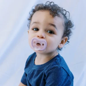 product shot looking down from above of baby boy brushing teeth and soothing himself with the calm and clean pacifier toothbrush from froglily baby