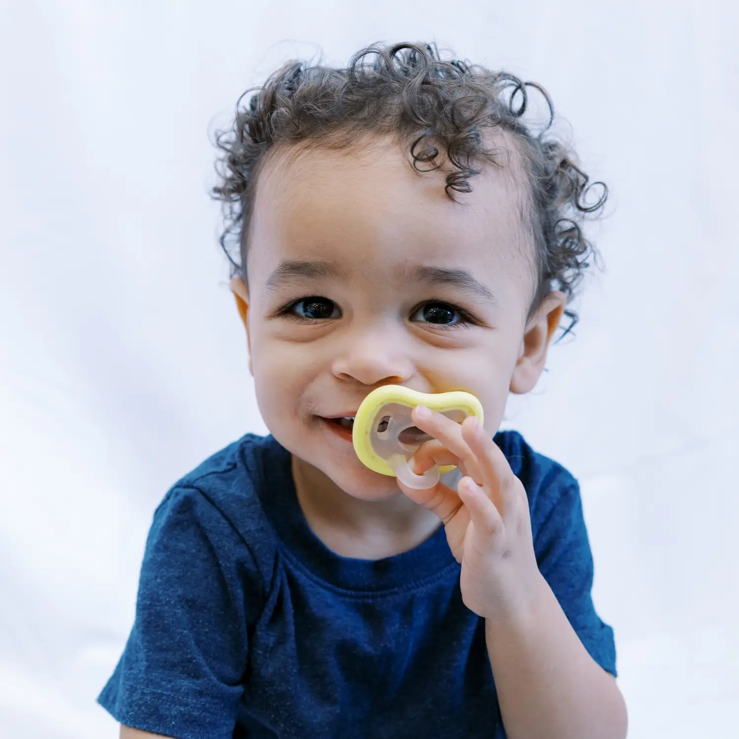 product shot looking down from above of baby boy brushing teeth and soothing himself with the calm and clean pacifier toothbrush from froglily baby