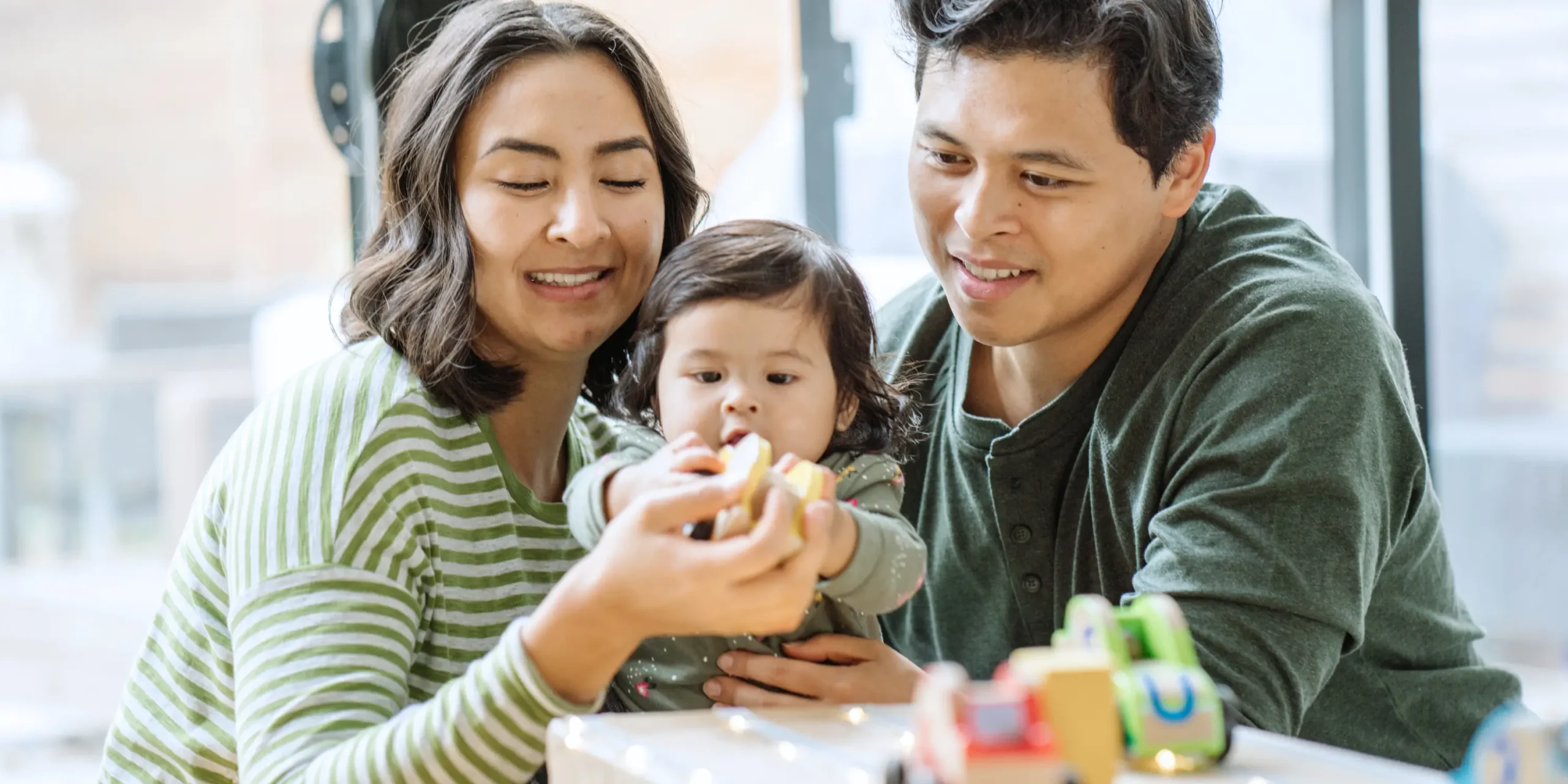 mother and father engaged in play with their infant
