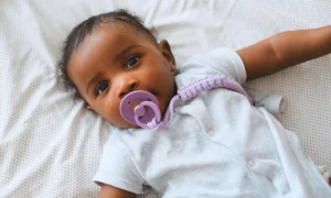 black baby soothing with a pacifier in bed