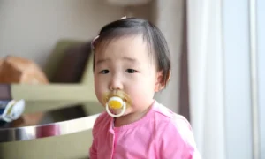 asian baby soothing herself with a pacifier
