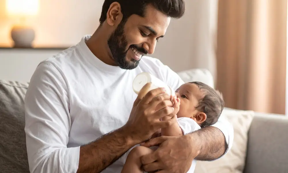 father holding newborn baby giving a bottle infant caries baby bottle tooth decay risks and treatment